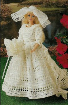 a crocheted doll wearing a white dress and bonnet with flowers in the background