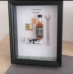 a shadow box with some items in it and a bottle on the table next to it