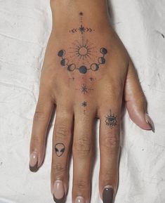 a woman's hand with tattoos on it, including an eye and stars tattoo