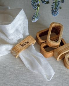 three wooden napkin holders sitting on top of a white table cloth next to blue flowers