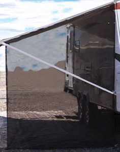 an rv parked in the desert with its reflection on it's glass side door