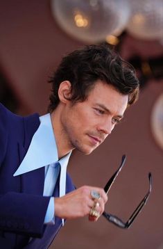 a man wearing a blue suit and holding a pair of scissors in his right hand