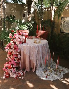 a table with pink flowers and candles on it