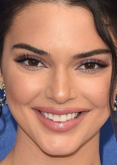 a close up of a person wearing large earrings and smiling at the camera with her eyes wide open