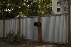 a metal fence with a mailbox on the side and trees in the back ground