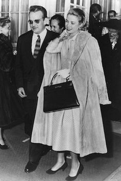 an old black and white photo of two women in coats, one carrying a handbag