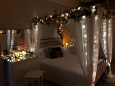 a bedroom decorated with lights and flowers on the headboard, along with a canopy bed