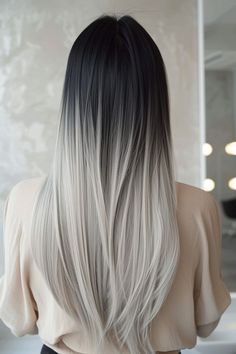 the back of a woman's head with long black and white hair in front of a mirror