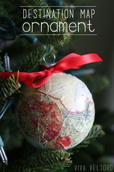 a christmas ornament hanging from the top of a tree with red ribbon on it