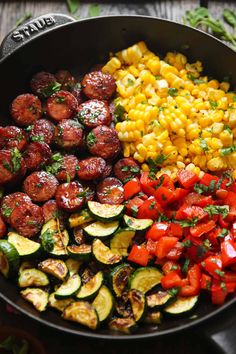 a skillet filled with vegetables and corn on the cob next to other foods