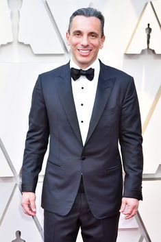 a man in a tuxedo and bow tie on the oscars red carpet