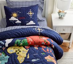 a bed covered in blue and white sheets with world map pillows on top of it