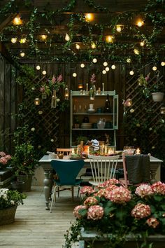 an outdoor dining area with potted plants and lights hanging from the ceiling above it