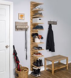 a wooden shelf filled with shoes next to a white door and a basket on the floor