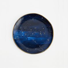 a blue and gold plate with stars on the top, against a white wall background