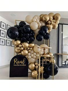 black and gold balloons are stacked on top of each other in the middle of a room