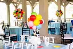 tables with chairs and balloons on them at a party