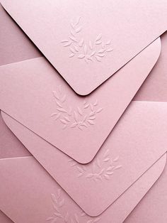 several pink envelopes with white embosishment on them