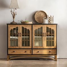 a wooden cabinet sitting on top of a tiled floor next to a lamp and vase