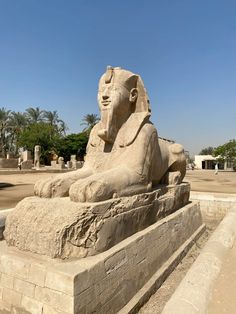 the large statue is sitting in front of some trees