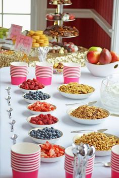 a table topped with plates and bowls filled with food next to desserts covered in pink cups