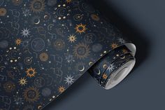 a wallpaper with gold stars and moon designs on black background, as well as a roll of wrapping paper