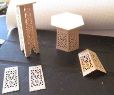 four pieces of laser cut wood sitting on top of a black table next to a roll of paper