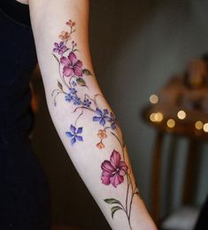 a woman's arm with flowers and leaves tattooed on the left side of her arm