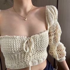 a close up of a woman wearing a white crop top with crocheted sleeves