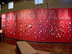 a red wall with writing on it that says giving wall hanging from the ceiling, and several pieces of string attached to the wall