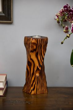 a wooden candle holder sitting on top of a table next to a vase with flowers