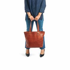 Our classic tote is handcrafted in luxuriously soft, vegetable-tanned American leathers. Spacious, durable, and versatile this tote is ideal for everyday use. For added security, the tote features a large zip-top canvas pouch that snaps in at the sides and can be removed for easy cleaning. A drop-in pocket holds your phone, keys and other small items. Easily convert the tote to a crossbody bag by clipping the optional strap into interior D rings. Crafted by artisans for a lifetime of daily use, the Range Tote features premium metal hardware and elegant finished edges. It can accommodate a laptop up to 14 inches. Our leathers are carefully selected for their natural appearance and regenerative sourcing -- they come from rangelands managed in alignment with nature. Variations in tone, marks Interior D, American Leather, Signature Hardware, D Rings, Zip Pouch, Canvas Pouch, Metal Hardware, Zip Top, Small Items