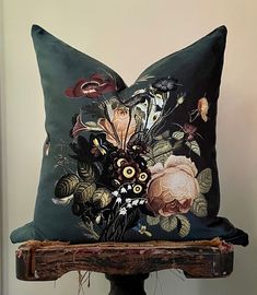 a black pillow with flowers on it sitting on a wooden stand