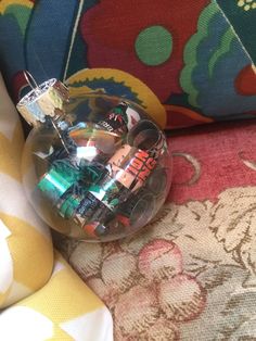 a glass ball ornament sitting on top of a colorful fabric covered couch next to a pillow