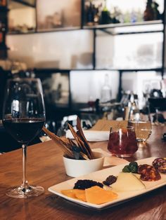 a wooden table topped with glasses of wine and plates of food on top of it