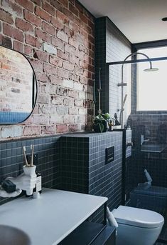 a bathroom with a brick wall, toilet and sink in front of a window that looks out onto the street