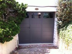 an entrance to a house with two doors and some bushes on the side of it