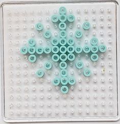 there is a snowflake made out of plastic buttons on the tray with holes in it