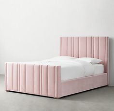 a pink bed with white sheets and pillows on top of it, in front of a wall