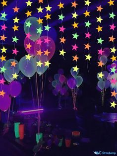 stars and balloons are hanging from the ceiling at a birthday party or celebration with glow in the dark colors