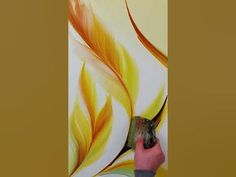 a person painting a wall with yellow and orange colors