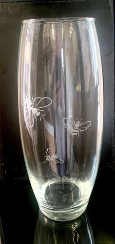 a clear glass vase sitting on top of a black table next to a bottle opener