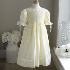 This Gorgeous Strasburg Pastel Pale Yellow Hand-Smocked Girls Float Style Dress Is In Perfect Condition. The Bodice Is Completely Hand Smocked In Yellow And White And Has White Embroidered Flower Details With Yellow Centers. The Gathered Puff Sleeves Are Trimmed In White Satin Ribbon Which Ties In A Bow And Are Finished Off With A Delicate Crocheted Cotton Lace. The Skirt Has A Lovely White Satin Ribbon Band With An Attached Delicate Crocheted Cotton Lace Trim. The Dress Is Fully Lined And Has A Button Back Closure With A Sash That Ties Into A Bow. Great For Weddings, Church, Portraits, Vacation Or Any Special Occasion. Fits Size 4/5 (See Measurements For Fit). Matching Sister/Cousin Dresses Matching Sisters, Hand Smock, Little Dresses, White Satin, Pale Yellow, Cotton Lace, Embroidered Flowers, Satin Ribbon, Kids' Dresses