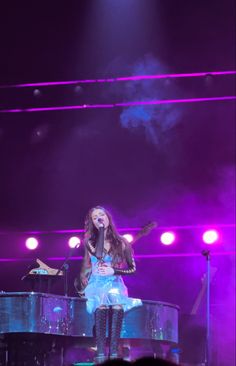 a woman standing on top of a piano in front of a crowd at a concert