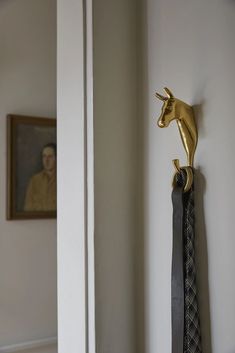 a tie hanging on the wall next to a horse head and an old man's portrait