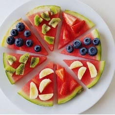 a white plate topped with slices of watermelon, kiwi and blueberries