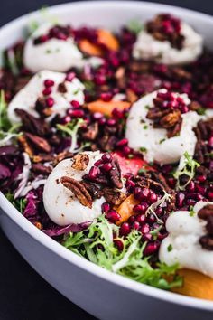 a white bowl filled with salad topped with meat and pomegranate