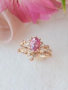 a pink diamond ring sitting on top of a flower