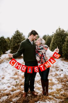 a man and woman holding up a christmas sign