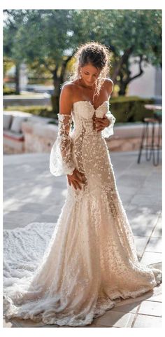 a woman in a wedding dress is looking down at her phone while standing on the sidewalk